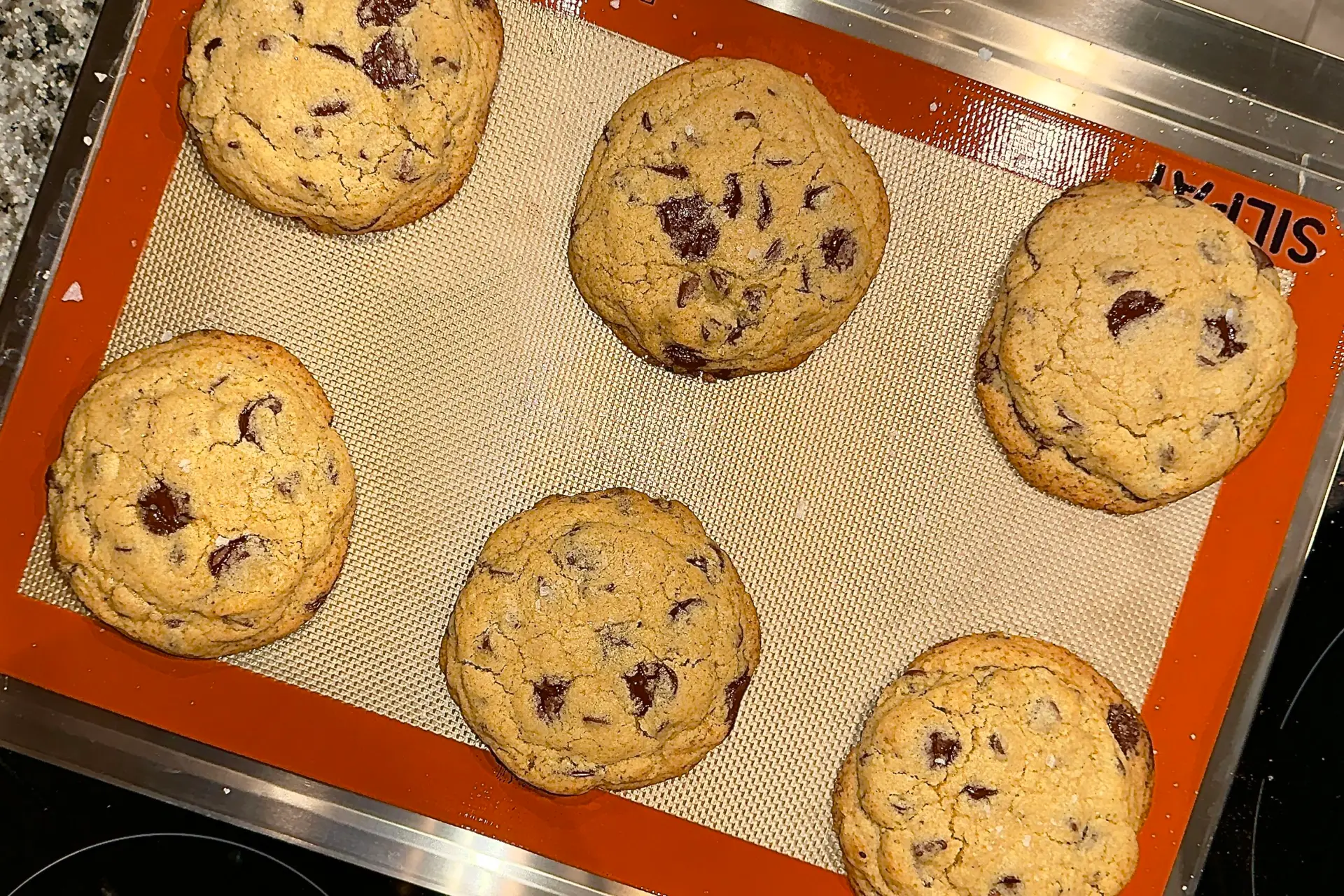 6 chocolate chip cookies on silpat over cookie sheet